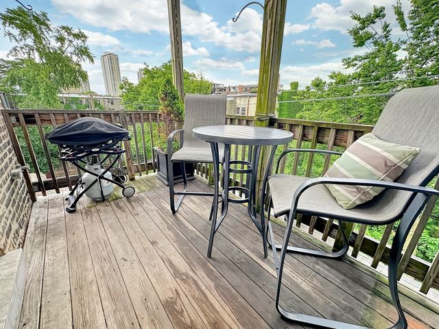 a view of deck with table and chairs a barbeque with wooden floor and fence