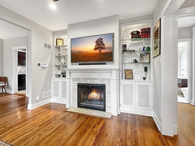 a living room with stainless steel appliances furniture a fireplace and wooden floor