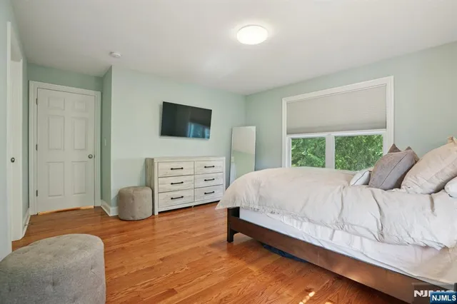 a bedroom with a bed and a flat tv screen on dresser
