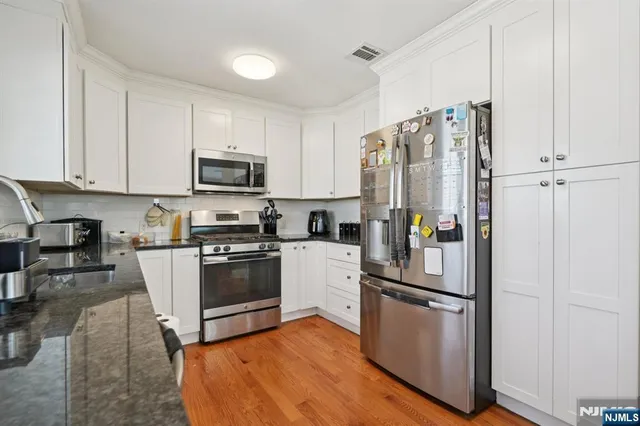 a kitchen with granite countertop a refrigerator stove and microwave