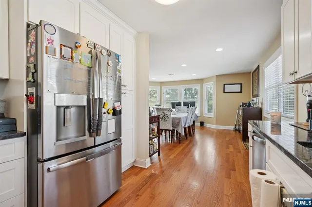 a kitchen with stainless steel appliances a refrigerator a stove and a dining table with wooden floor