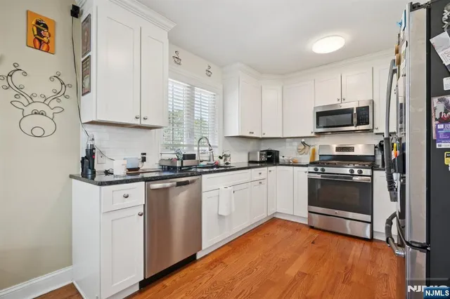 a kitchen with stainless steel appliances granite countertop a stove top oven a sink and white cabinets