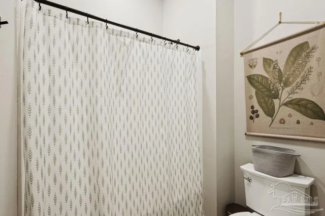 a bathroom with a toilet and a shower curtain