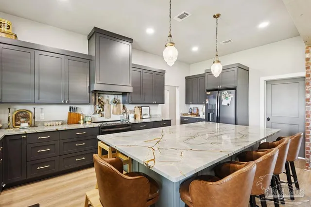 a kitchen with stainless steel appliances granite countertop a sink a stove and chairs