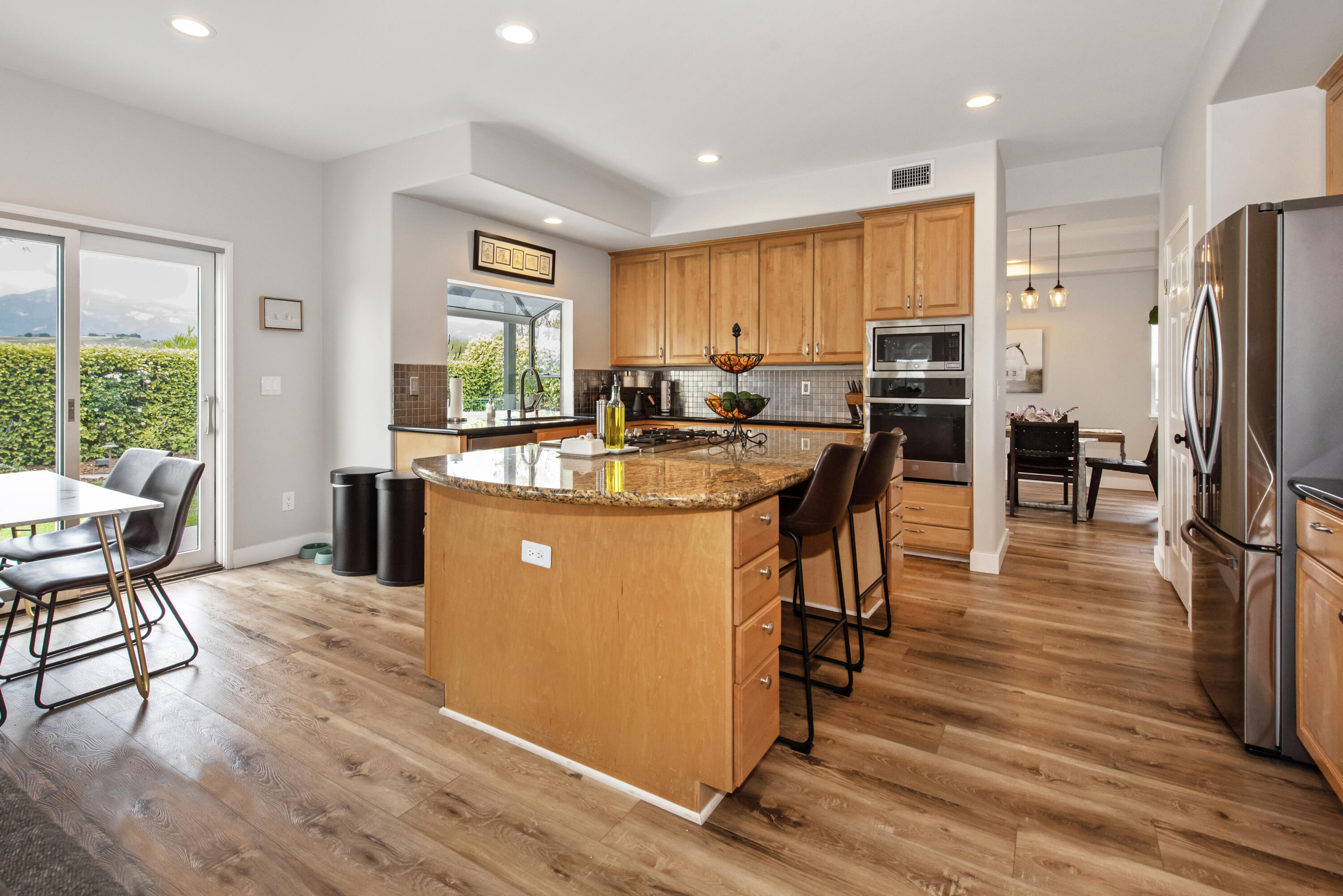 7906 Winchester Circle Goleta, CA 93117 - Photo 7 of 26 a kitchen with stainless steel appliances granite countertop a refrigerator a stove top oven a sink dishwasher and dining table with wooden floor