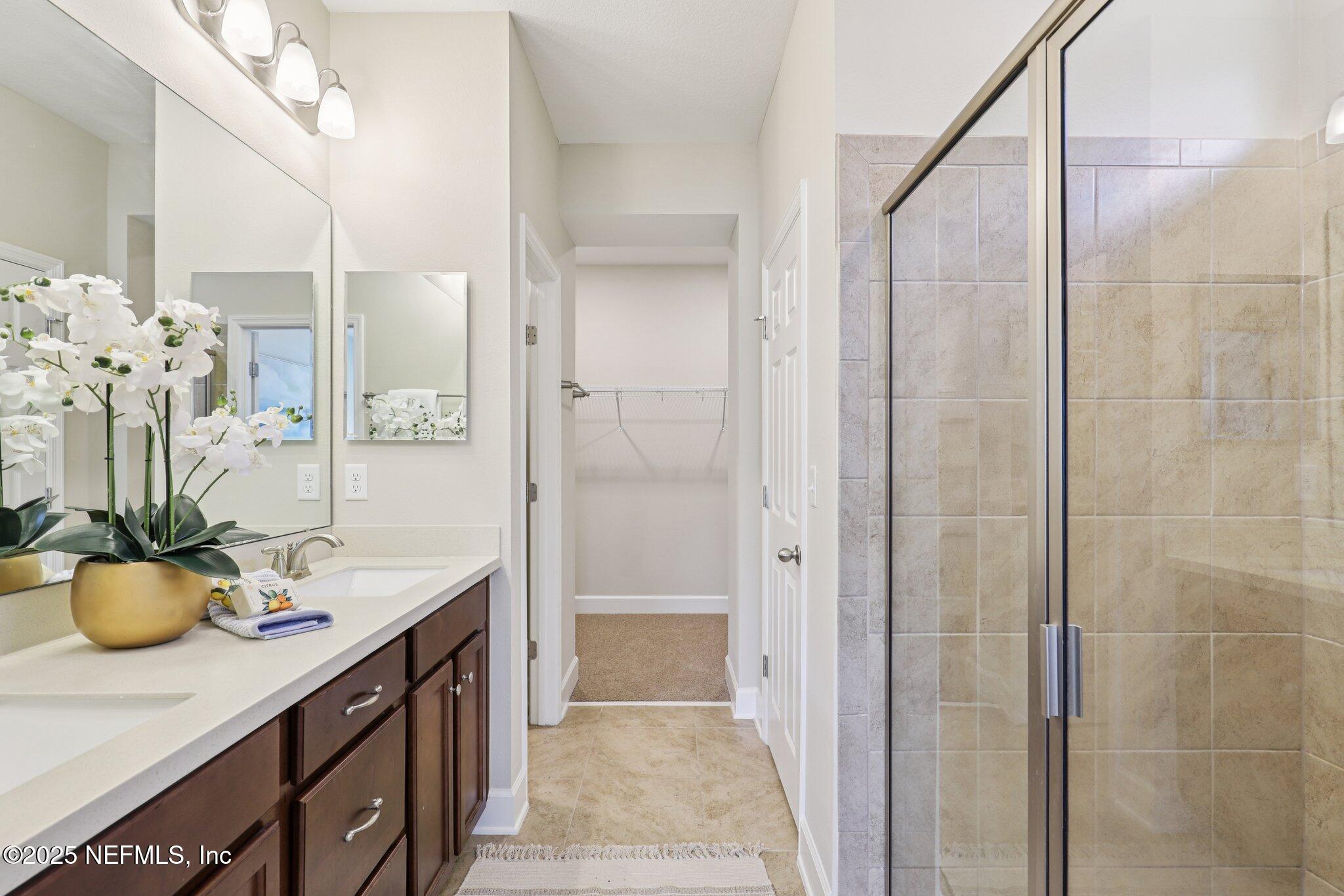 48 Gilchrist Way St. Augustine, FL 32092 - Photo 24 of 50 a bathroom with a granite countertop sink a large mirror and a shower