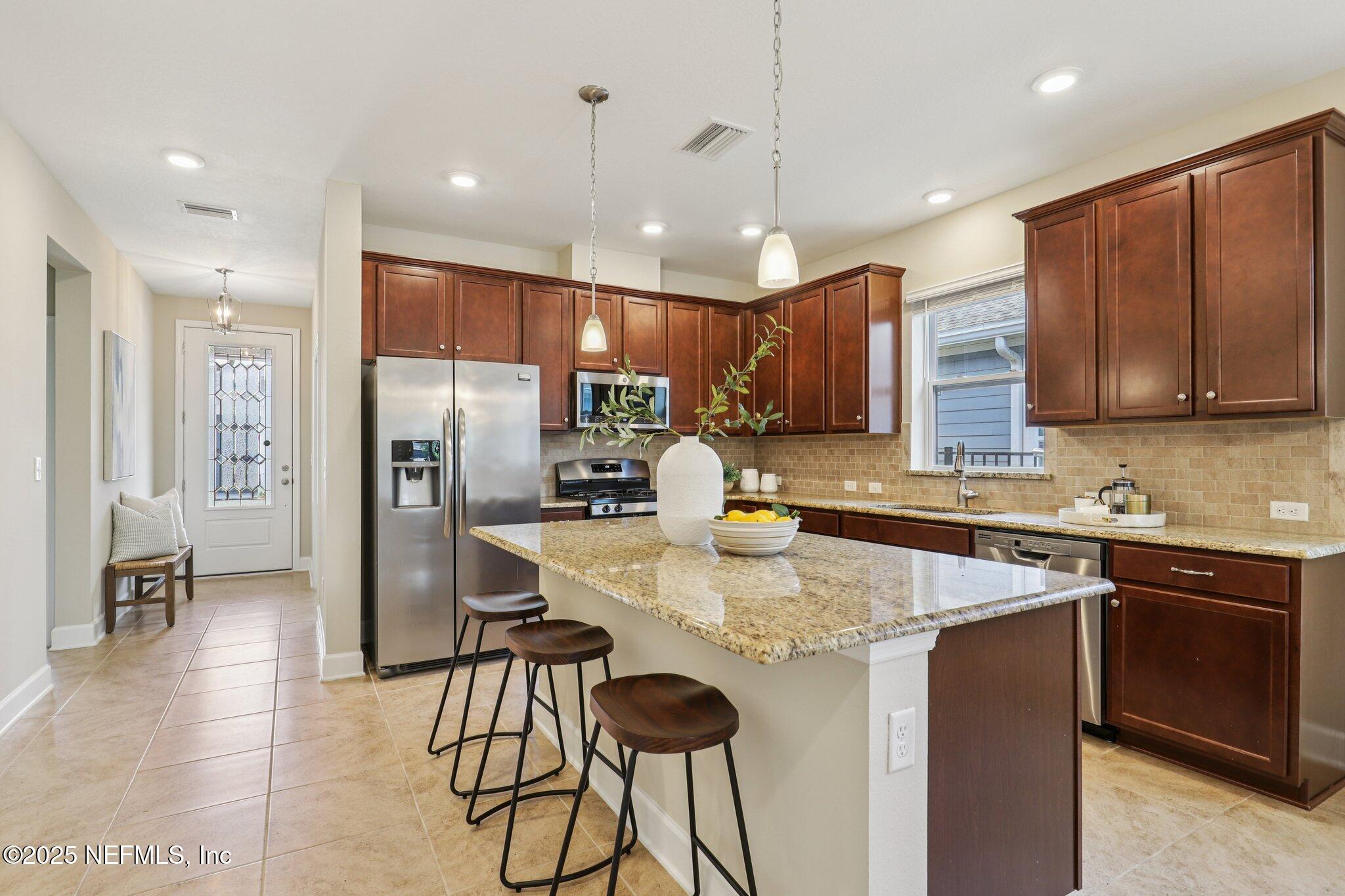 48 Gilchrist Way St. Augustine, FL 32092 - Photo 9 of 50 a kitchen with stainless steel appliances granite countertop a sink a stove a refrigerator cabinets and chairs