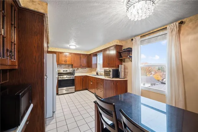 a kitchen with stainless steel appliances kitchen island granite countertop a refrigerator a oven a sink with wooden cabinets and wooden floor