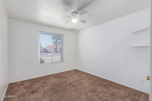 an empty room with windows and ceiling fan