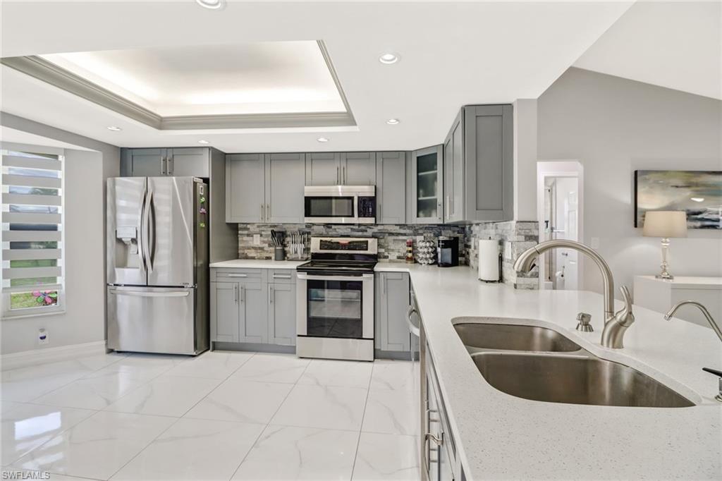 5131 31st Place Southwest Naples, FL 34116 - Photo 6 of 24 a kitchen with kitchen island a sink stove and refrigerator