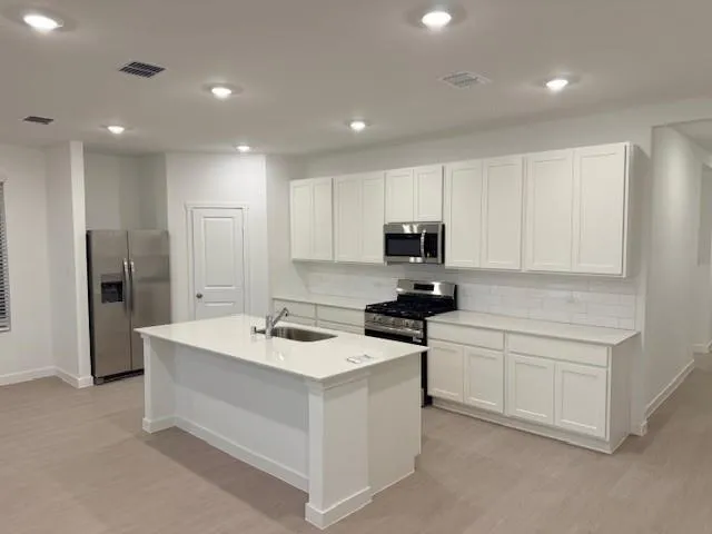 a kitchen with white cabinets and stainless steel appliances
