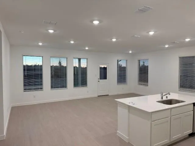 a view of an empty room with floor to ceiling window and kitchen