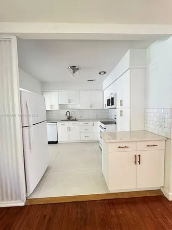 a kitchen with stainless steel appliances granite countertop a refrigerator a stove and white cabinets with wooden floor