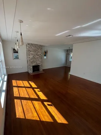 a view of empty room with wooden floor and fireplace