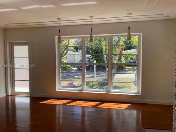 a view of an empty room with wooden floor and a window