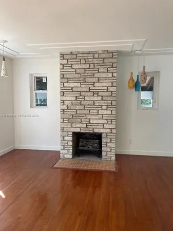 a view of an empty room with wooden floor and a fireplace
