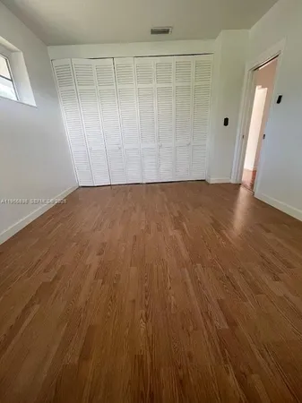 an empty room with wooden floor and entrance