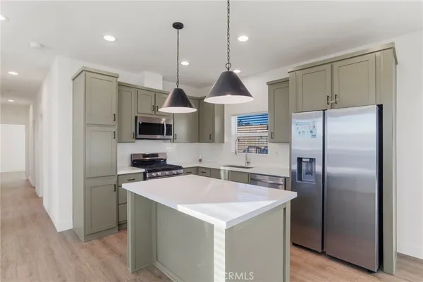 a kitchen with stainless steel appliances a refrigerator a sink a stove a microwave and wooden floor