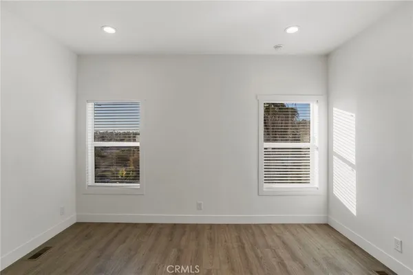 an empty room with wooden floor and windows
