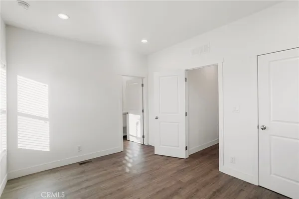 a view of an empty room with wooden floor and closet
