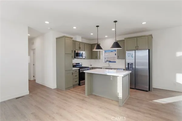 a kitchen with stainless steel appliances kitchen island a refrigerator sink and cabinets