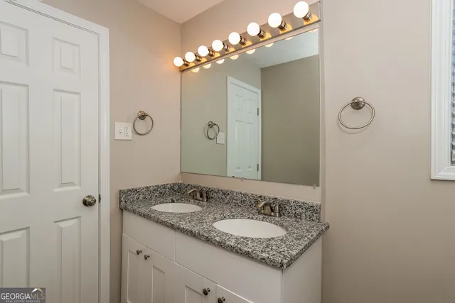 a bathroom with a granite countertop sink a large mirror and a shower