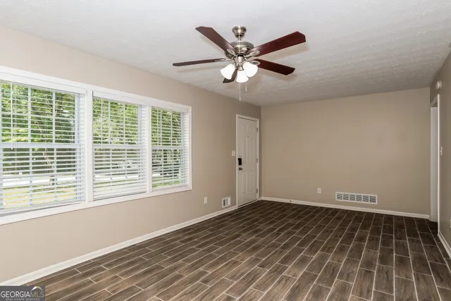 a view of an empty room with wooden floor and a window