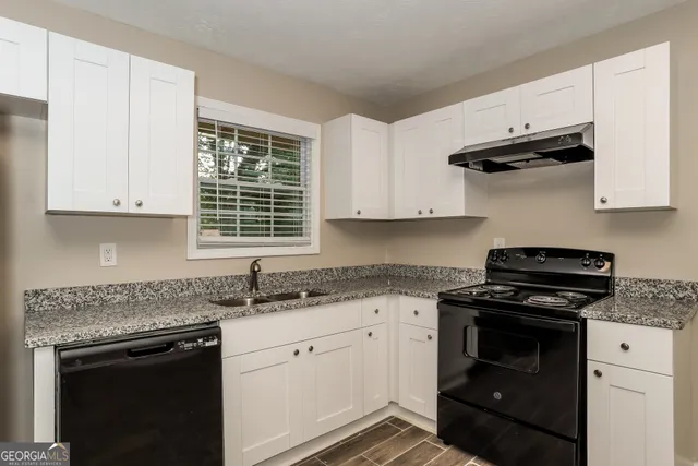 a kitchen with granite countertop white cabinets and a stove top oven