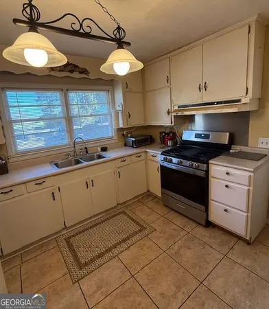 a kitchen with stainless steel appliances granite countertop a sink a stove and a window