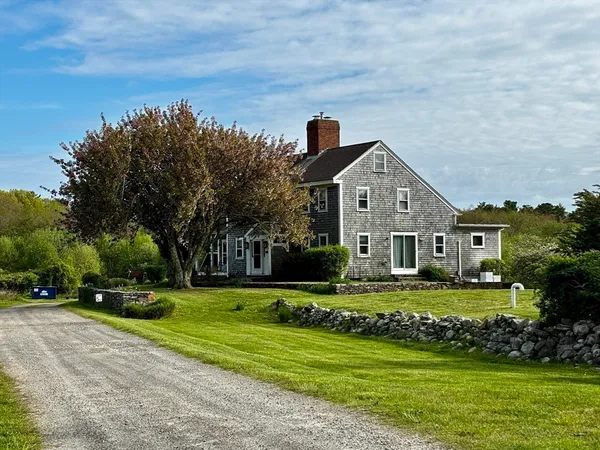 a front view of a house with a garden and trees