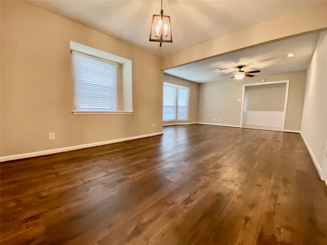 a view of an empty room with glass door and a chandelier fan