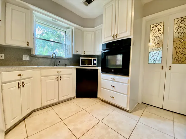 a kitchen with white cabinets and appliances
