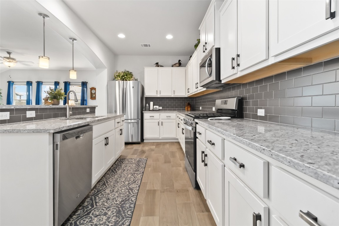 a kitchen with granite countertop a sink a counter top space stainless steel appliances and cabinets
