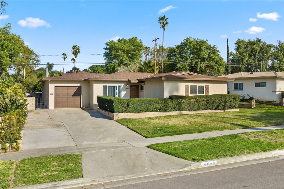 Classic curb appeal with attached garage, extended driveway, and a spacious front lawn.