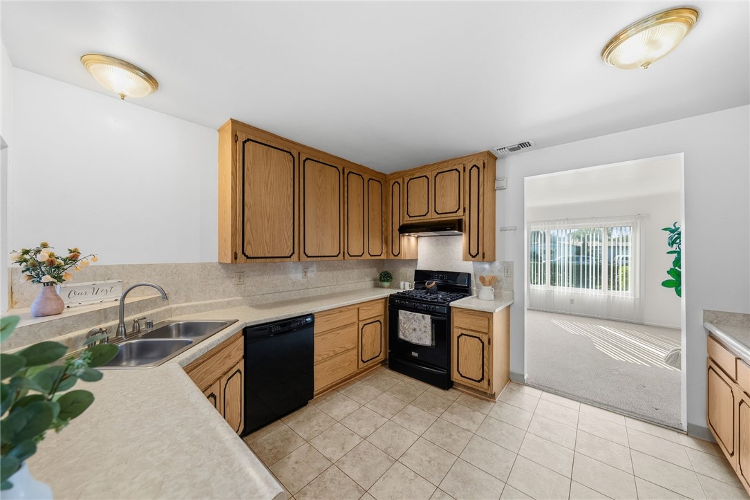 3075 David Street Riverside, CA 92506 - Photo 11 of 40 L-shaped kitchen featuring a double-basin sink, dishwasher, and gas range, with a bright connection to the adjoining room.