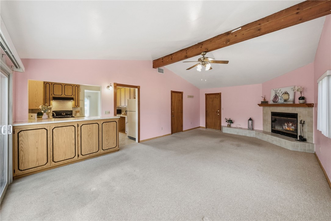 3075 David Street Riverside, CA 92506 - Photo 13 of 40 Spacious living area with vaulted ceiling, exposed beam, and an inviting fireplace, plus an open connection to the kitchen and dining space.