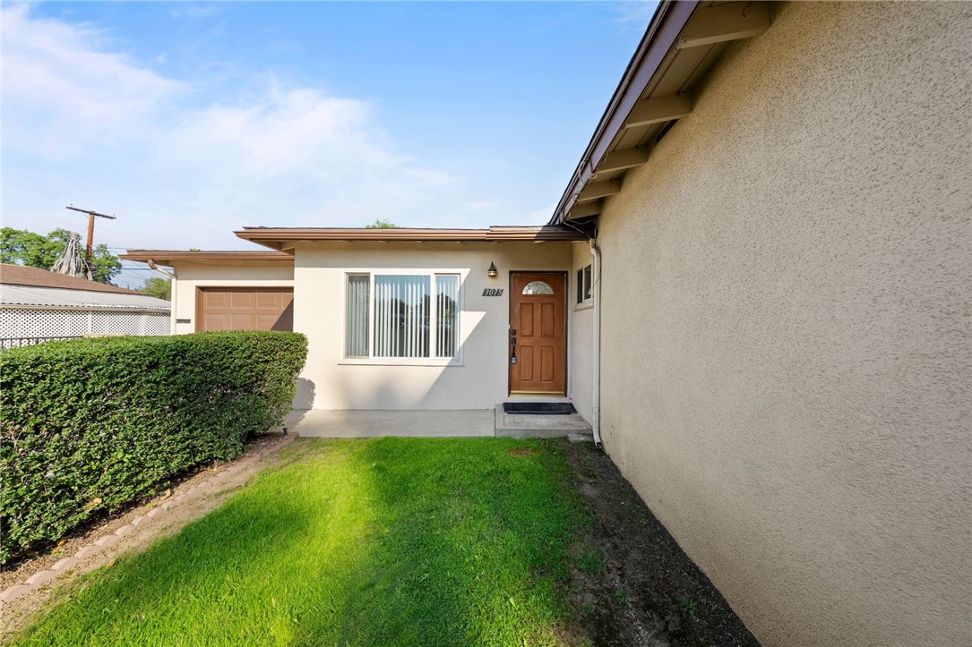 3075 David Street Riverside, CA 92506 - Photo 38 of 40 Welcoming front entry with a tidy lawn and mature hedge, plus an attached garage and large front window.