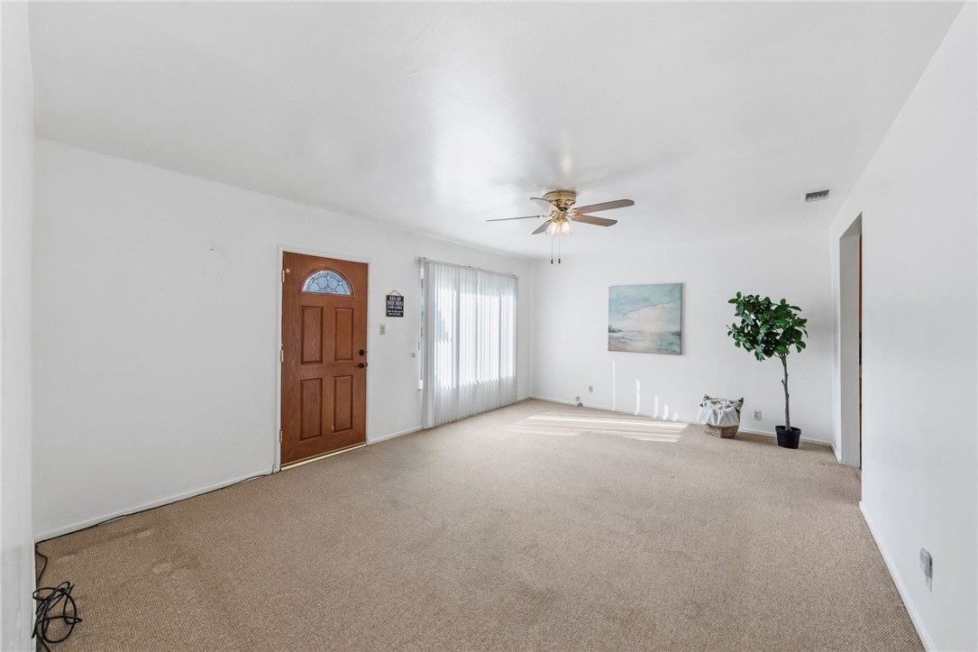 3075 David Street Riverside, CA 92506 - Photo 4 of 40 Large, open living area with plush carpeting, ceiling fan, and natural light through sliding glass doors.