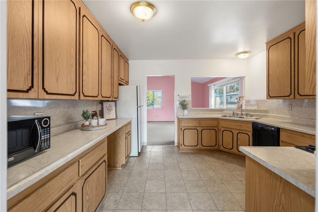 3075 David Street Riverside, CA 92506 - Photo 7 of 40 Long galley-style kitchen with plentiful cabinetry and counter space, plus a sunny window over the sink.