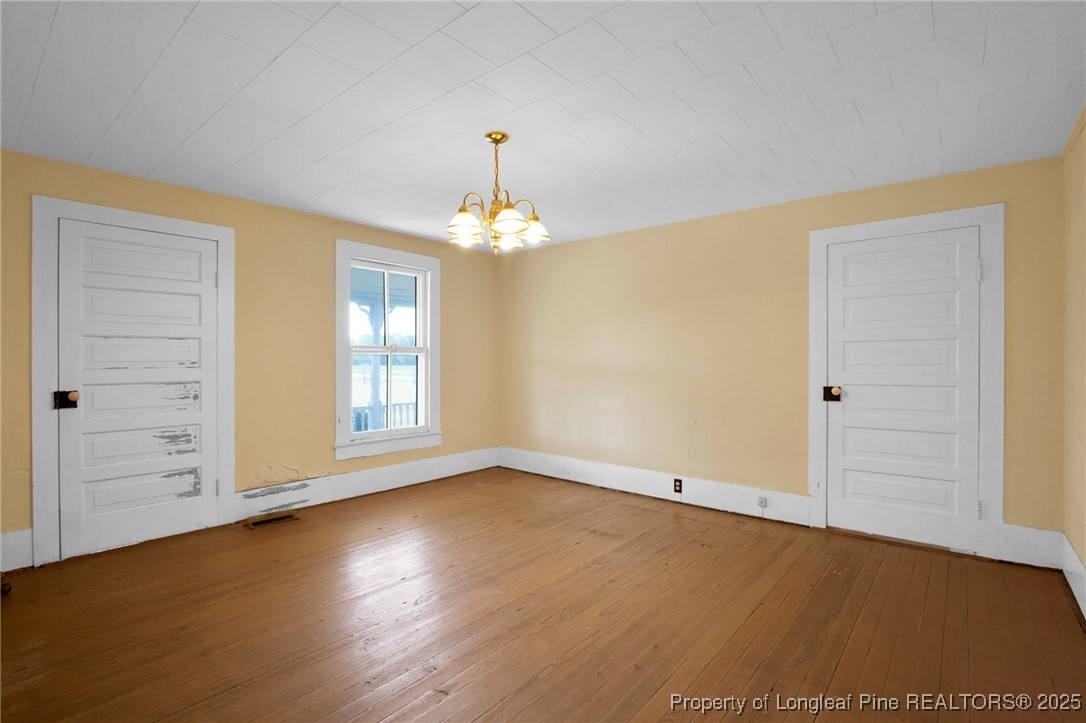 5125 Maxwell Road Autryville, NC 28318 - Photo 19 of 37 an empty room with wooden floor chandelier and windows