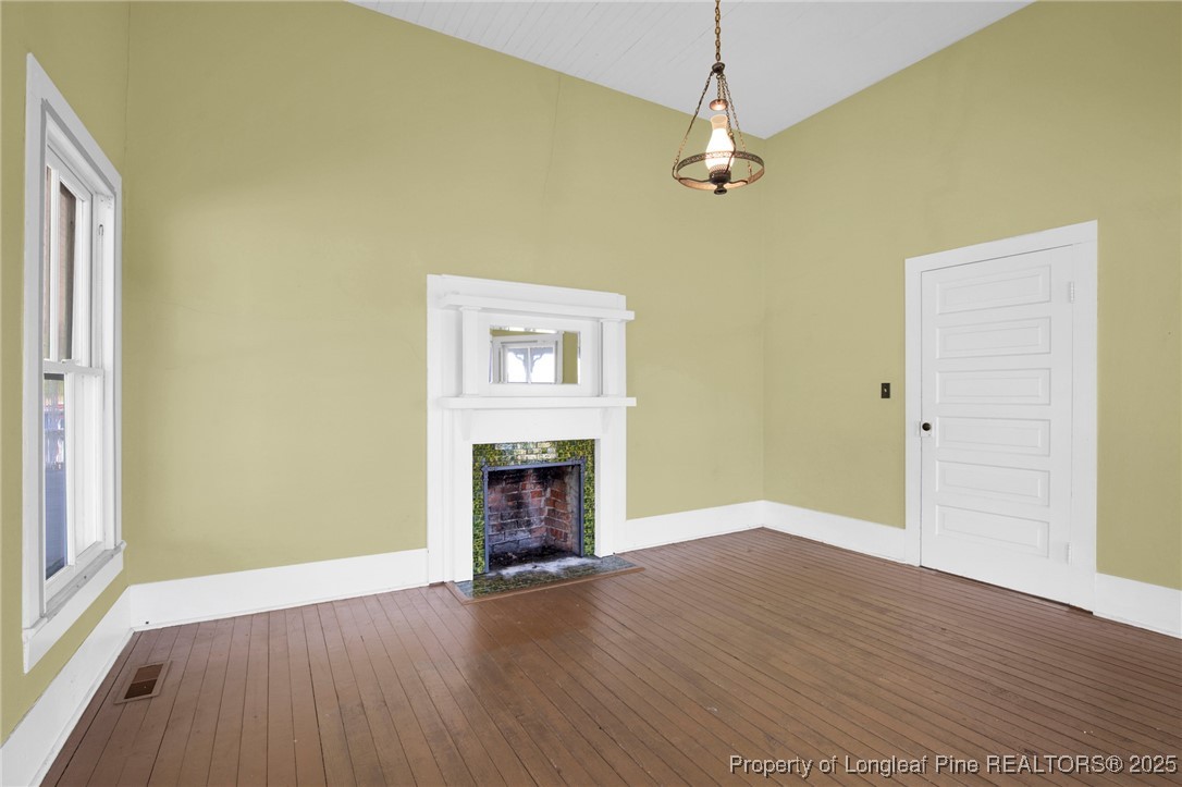 5125 Maxwell Road Autryville, NC 28318 - Photo 9 of 37 an empty room with a fireplace and wooden floor