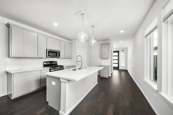 a large kitchen with stainless steel appliances granite countertop a stove a sink and a microwave