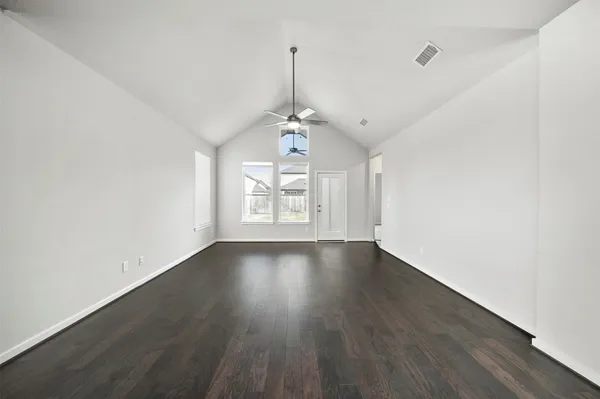 an empty room with a window and chandelier fan