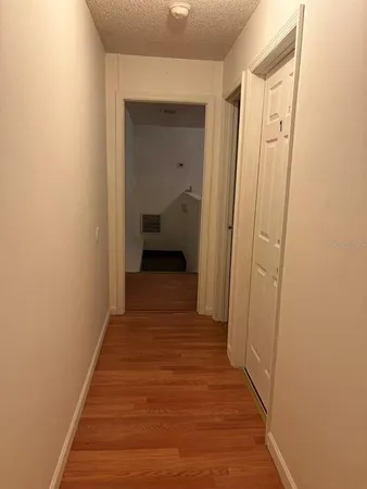 a view of a hallway with wooden floor and a bathroom