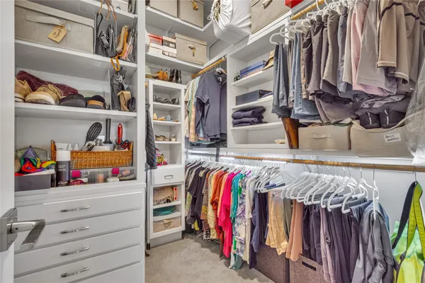 a view of walk in closet with clothes and shoes