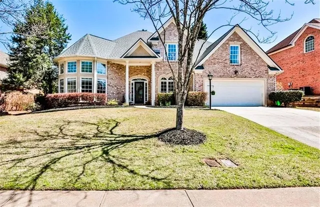 a front view of a house with yard and trees in the background
