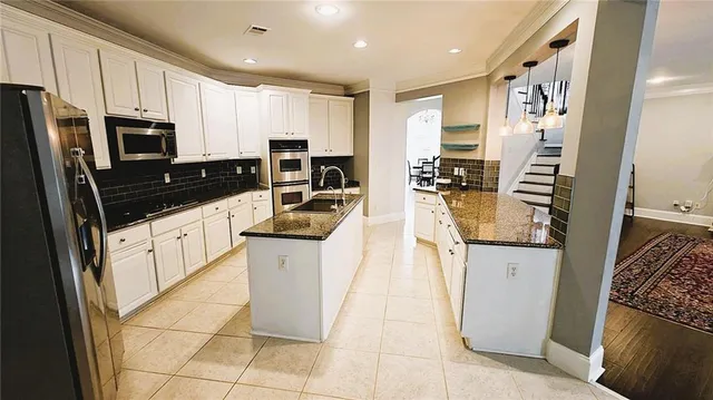 a kitchen with stainless steel appliances granite countertop a refrigerator a stove a sink and white cabinets