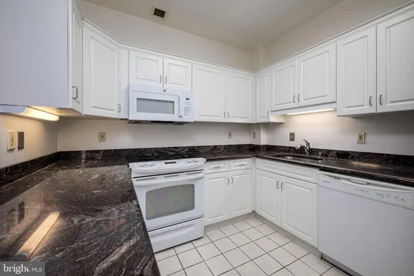 a kitchen with granite countertop white cabinets and stainless steel appliances