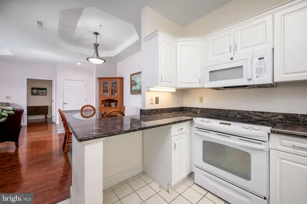 a kitchen with granite countertop a stove a sink a dining table and chairs