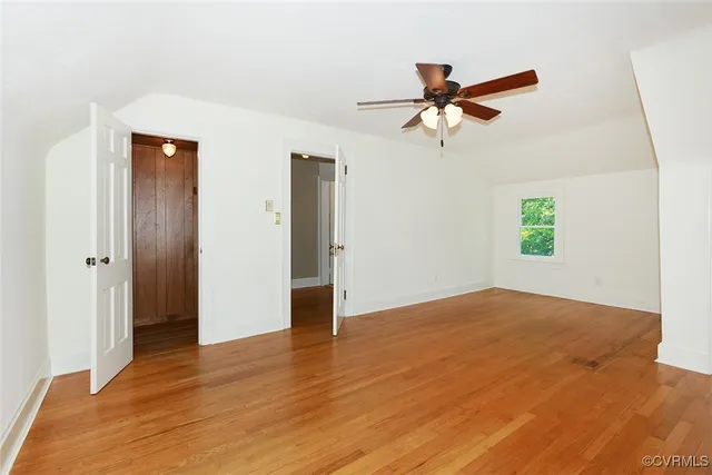 a view of empty room with wooden floor and ceiling fan